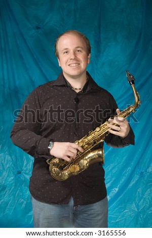 young balding man posing in front of portrait backdrop with saxaphone