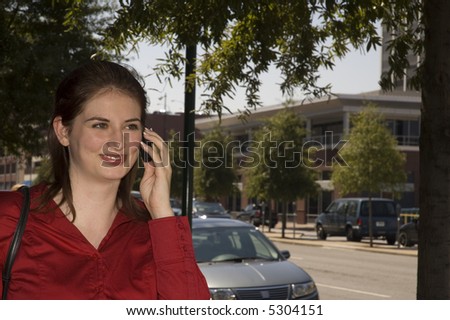Pretty girl talks on the cell phone as she walks down the street.