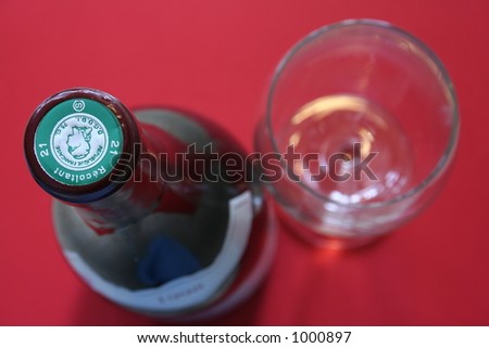 Top view of a wine bottle and red background. Shallow DOF. Focus is on the generic cork label.