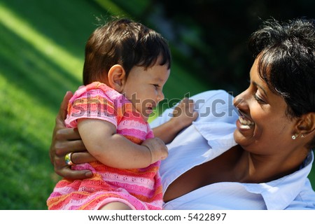 Very cute baby or toddler in bright pink clothings laughing with her mother. Concept: motherly love