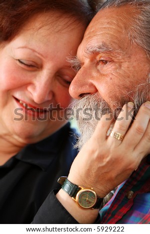 Affectionate old couple with the wife holding on lovingly to the husband\'s face. Focus on the husband\'s eyes. Concept: Elderly love.