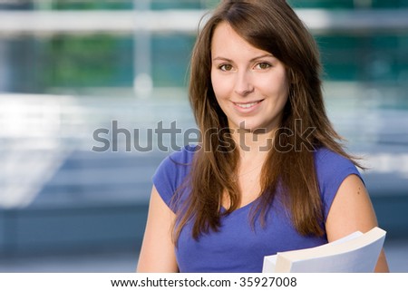 Pretty attractive caucasian white girl standing outside modern college school with books