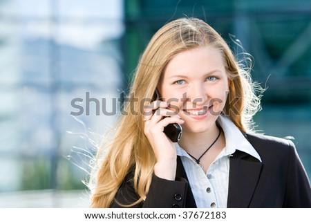 Blonde business woman in front of office building talking on cell mobile phone