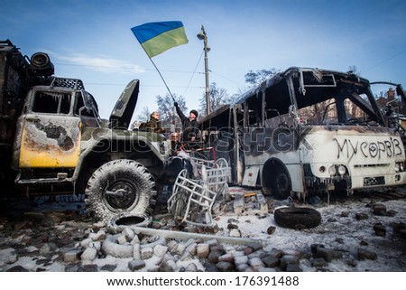 Burned cars on the street Hrushevskoho. Man waving flag of Ukraine. Ukraine, Kiev, street Hrushevskoho (01/20/2014)