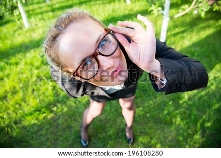 Girl in a business suit holding his hands over the rim glasses, looking strictly at frame