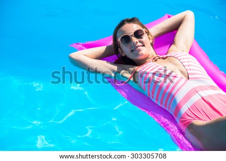 The girl floats on an inflatable mattress in the pool