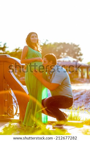happy young man kisses his pregnant wife belly