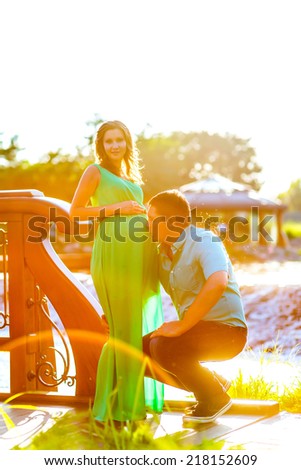 happy young man kisses his pregnant wife belly