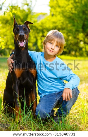 boy hugs his beloved dog or doberman in summer park