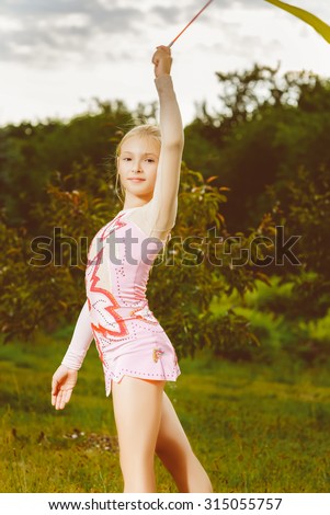 Young gymnast warms up with a gymnastic tape or feed. Warm toned image