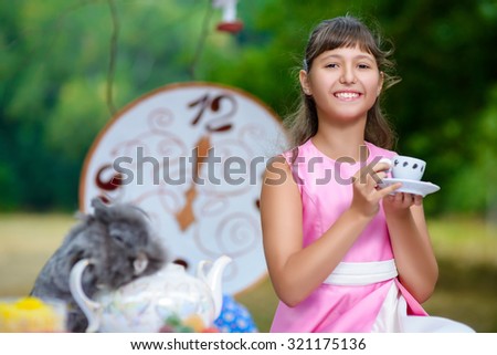 Girl sits at table and holding a cup of tea. Alice in Wonderland concept