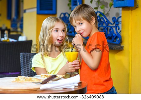 Surprised girl looks at the boy drinking juice