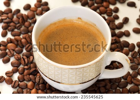 Cup of coffee and coffee beans (focus on foam)