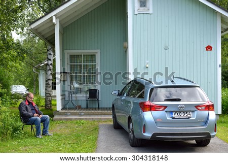 OULU, FINLAND - JULY 13, 2015:Nallikari Holiday Village-Camping is holiday resort near centre of Oulu on island Hietasaari. Near small cottage it is good to sit with book in shadow of trees