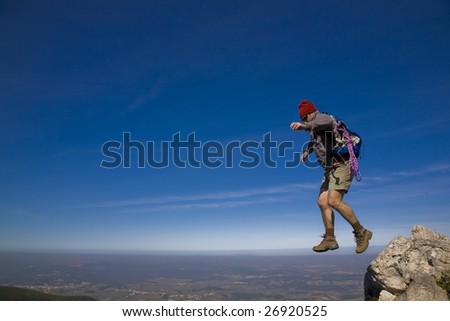 Leap of faith - A mountaineer jumping trough the rocks, over a clear blue sky