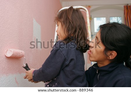 father helping his daughter to paint the wall