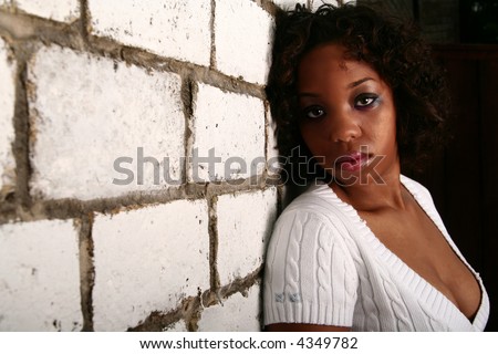 african american girl with innocent look showing blank expression leaning her back to white brick wall