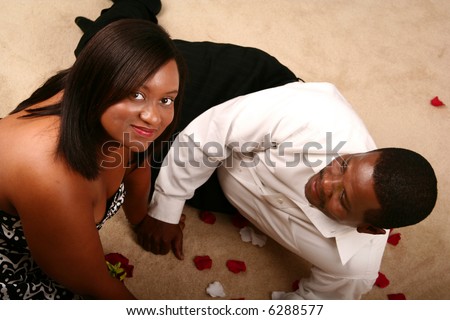 happy african american couple holding hand and relaxing on the floor. the man looking at his wife and she look at the camera