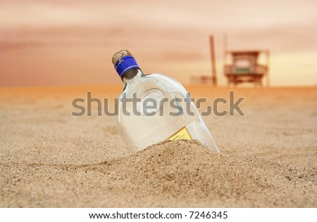 a message bottle covered with beach sand and beach guard\'s house on the background. sky showing sunsetting color
