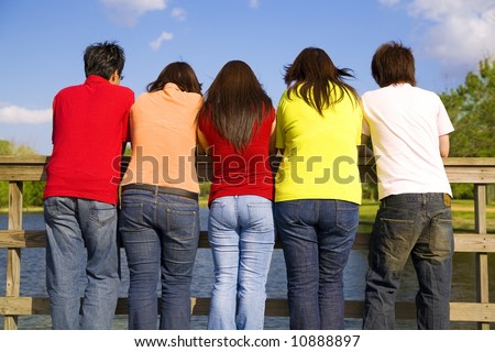 a group of asian teens turn their back on camera and looking at lake outdoor