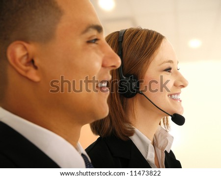 two business people, one of them wearing headset as customer service in light office environment looking to the side as if they are on meeting