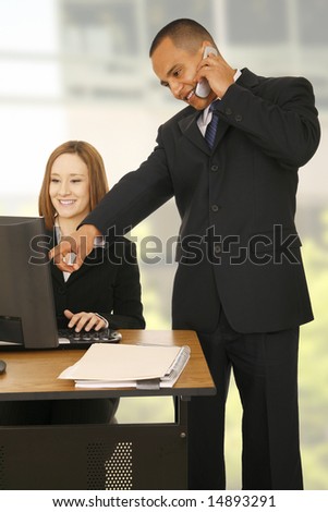 a man on the phone while pointing at computer screen while the other business woman looking at the screen and smiling. concept for business communication, or team work