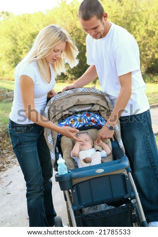happy young caucasian family take their baby on evening walk