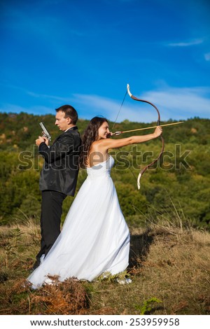Beautiful bride and groom with a gun and arrow