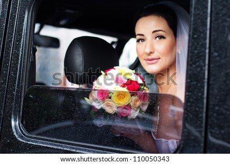 bride with a bouquet of roses sitting in the car