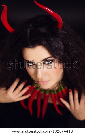 Devil. young woman portrait with red hot and spicy peppers
