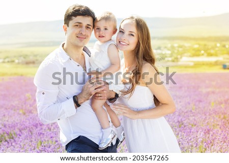 Happy family wearing white clothes mother, father and daughter having fun in lavender field