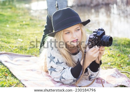 Cute little girl is resting near lake with camera