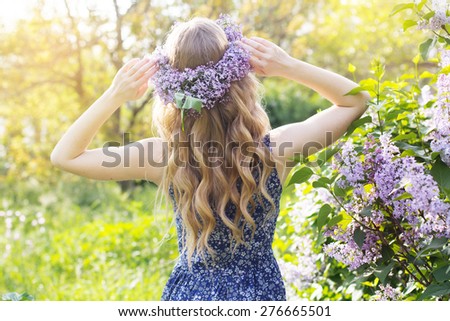Girl with wreath from lilac purple flowers in green park, spring time