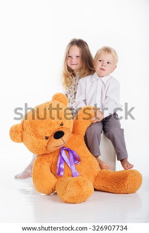 Beautiful happy couple boy and girl are embracing big brown teddy bear, isolated on white