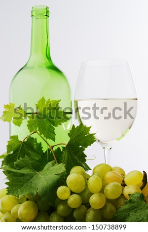 white wine glass and green wine bottle and green grape against white background