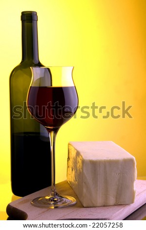 glass bottle of re wine and yellow cheese