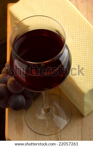a glass of red wine grape and yellow cheese