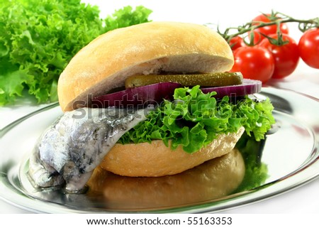 a roll with pickled herring, salad, onions and cucumber