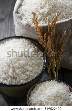 Rice in glass cup and a bag on wooden background