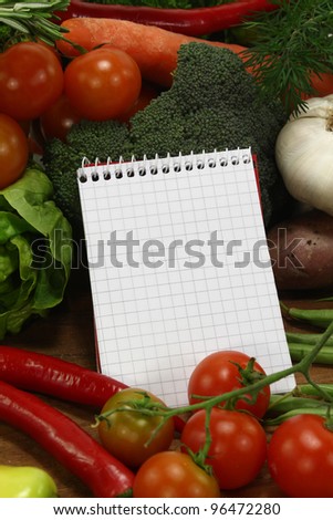 little plaid shopping list with fresh vegetables and pencil on a wooden background