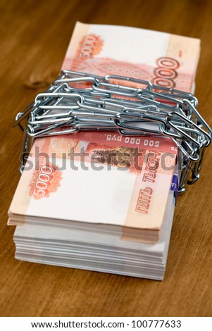 The money and  lock. Bundle of five thousand bank notes, preservation of capital