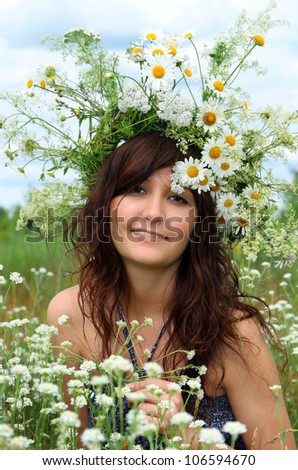 Portrait of the beautiful girl in a natural environment in diadem of wildflowers