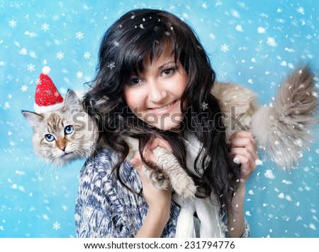 Charming young woman and siberian cat  in santa cap in snow