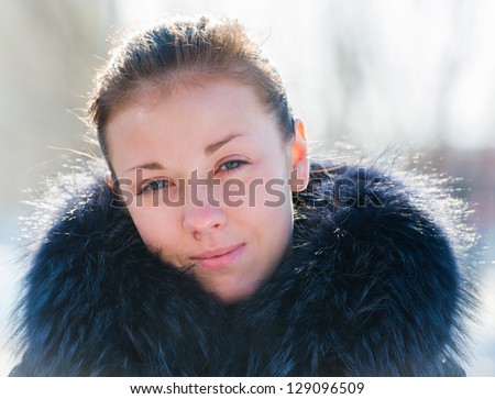 Portrait of a young girl in a fur collar sunlit