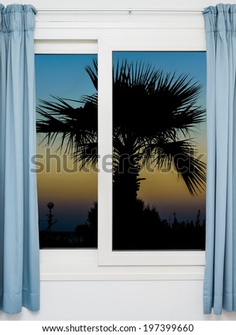 view from the window with the curtains of the sunset over the water