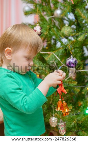 blond little boy dresses up Christmas tree toys