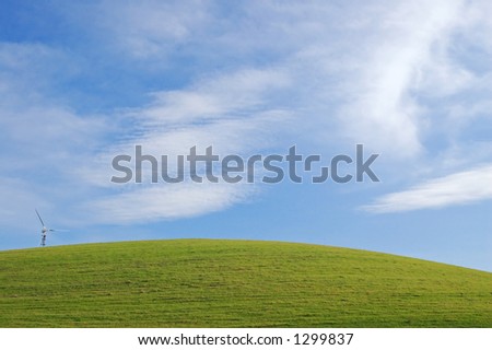 camera pointed at some grass in a field, with a windmill off to the side
