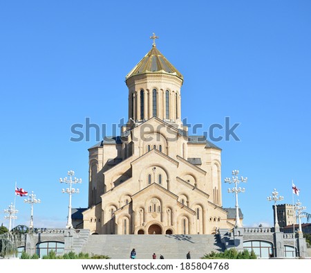 Tbilisi, Georgia - October 7, 2013: Georgian flags fluttering in the wind near the Holy Trinity Cathedral of Tbilisi (Tsminda Sameba) - one of the largest Orthodox churches in the world.
