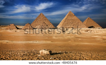 Near to the city of Cairo, in Sinai desert, against the pure blue sky and clouds, pyramids, an ancient miracle of the world have settled down