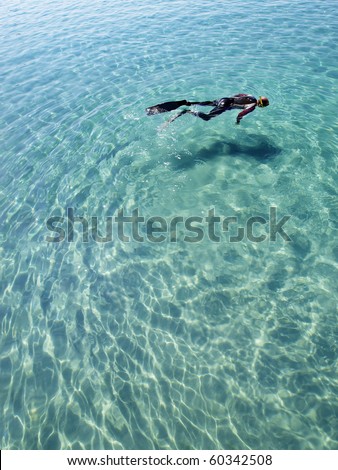 scuba diver in wet suit snorkeling in blue lagoon